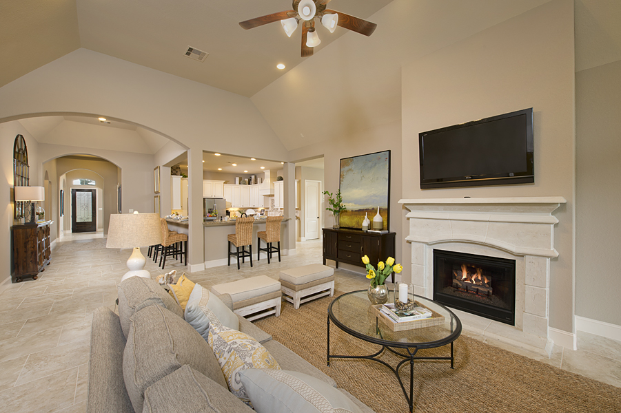 open-concept living room with cast stone fireplace, wrap around counter seating in kitchen and vaulted ceilings