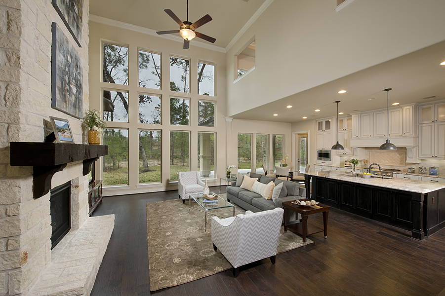 open-concept family room with stone fireplace, large windows, two-story vaulted ceiling, large kitchen island and wood floor