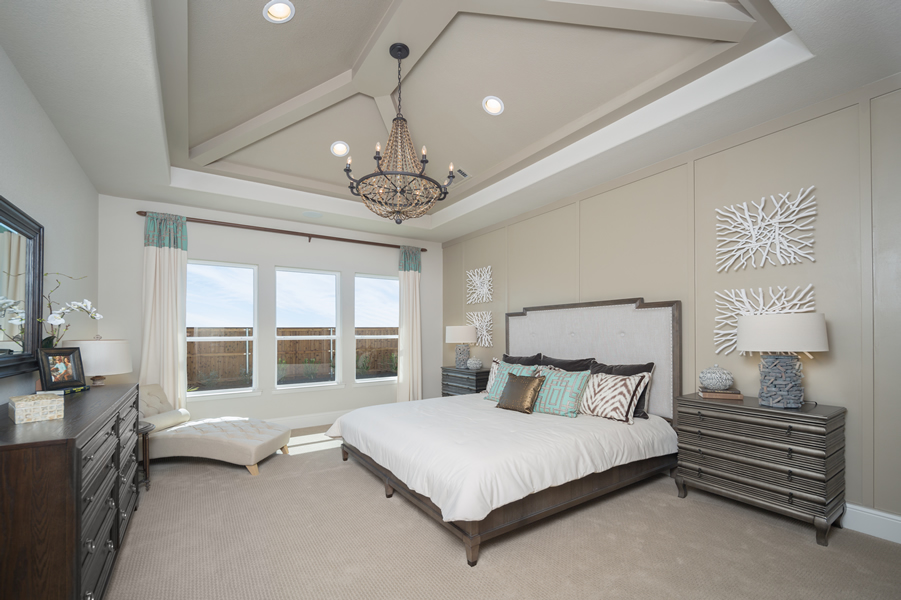 furnished master bedroom with beige accent wall, large picture windows, vaulted ceiling and chandelier