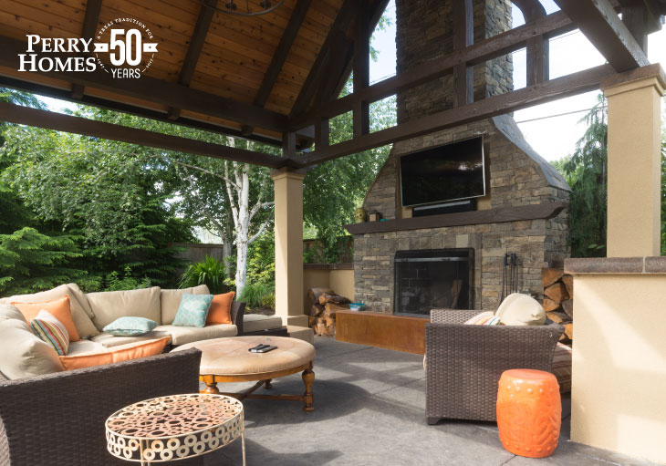 outdoor living space with large fireplace, outdoor tv and furniture, a tall vaulted roof with stucco pillars and wood trusses