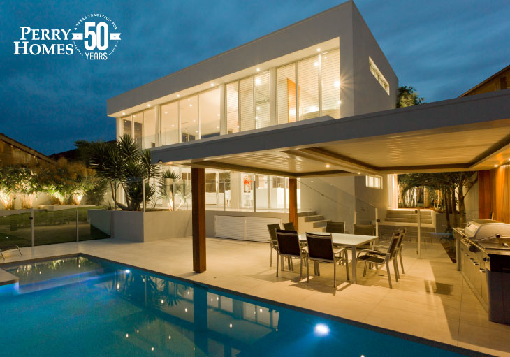 night view of backyard of white contemporary home with modern swimming pool and covered outdoor kitchen with dining area
