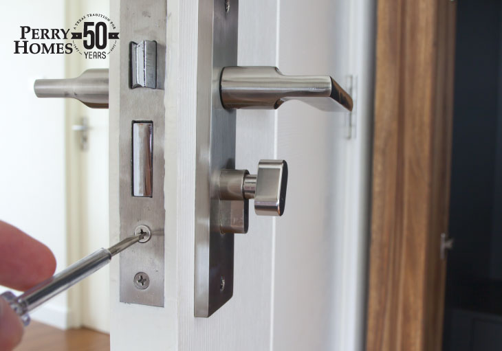 close up of brushed nickel lever door handle as a person adjusts screw underneath the door latch