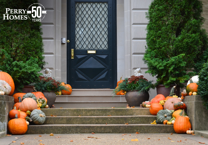 concrete steps leading to a black front door lined with different sizes and colors of pumpkins and squashes