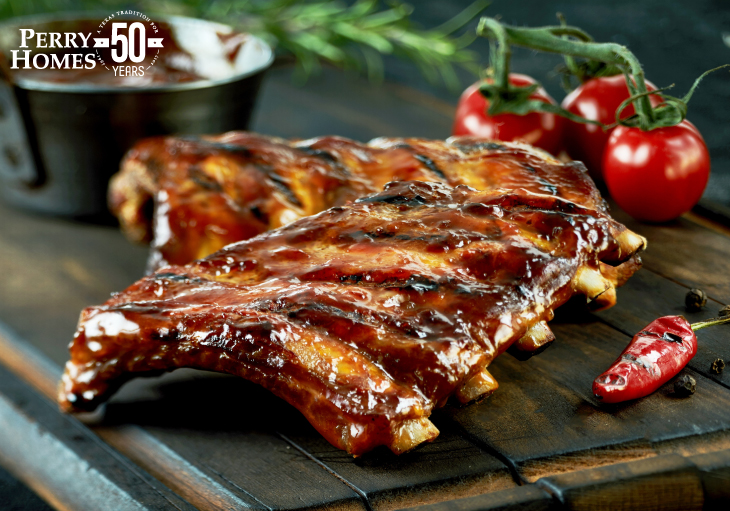 glazed barbecue ribs on slatted wood table with red tomatoes and grilled red pepper