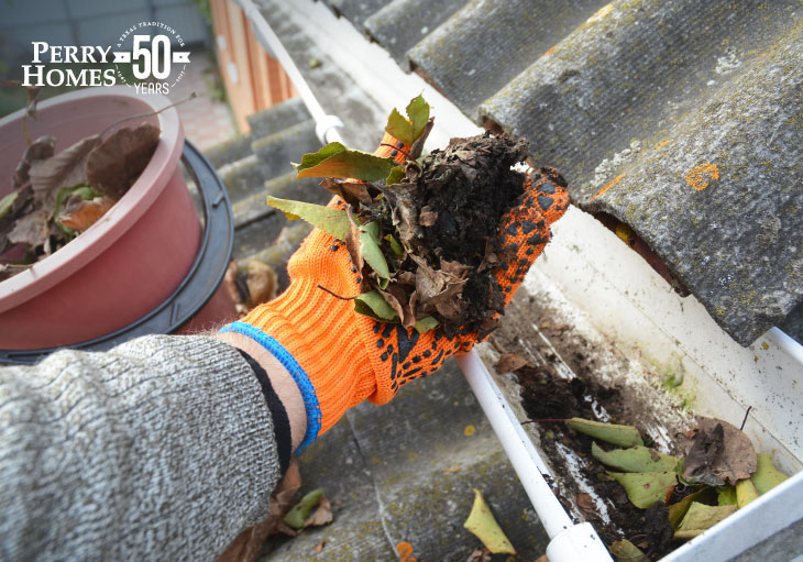gloved hand with pile of debris that was just taken out of clogged gutters during the fall season