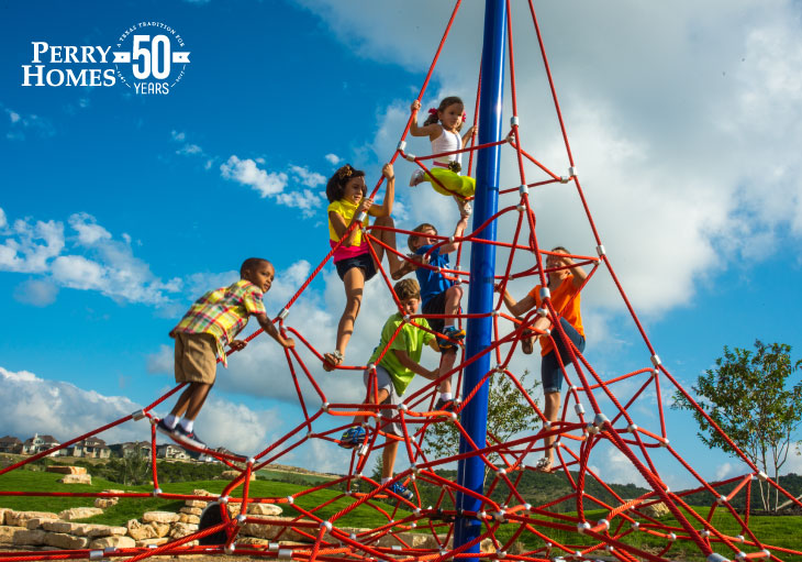 elementary aged children climbing on rope play structure on a partly cloudy day