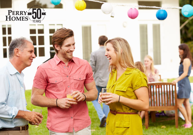 people standing and laughing while holding drinks at outdoor party during the summer