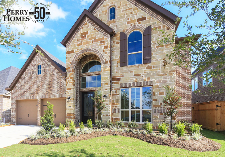 front exterior of brown and beige stone and brick two story home with two single garage doors and arched window with shutters