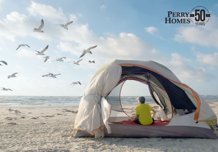 young man sitting in tent on beach watching gulls fly by during a partly cloudy day