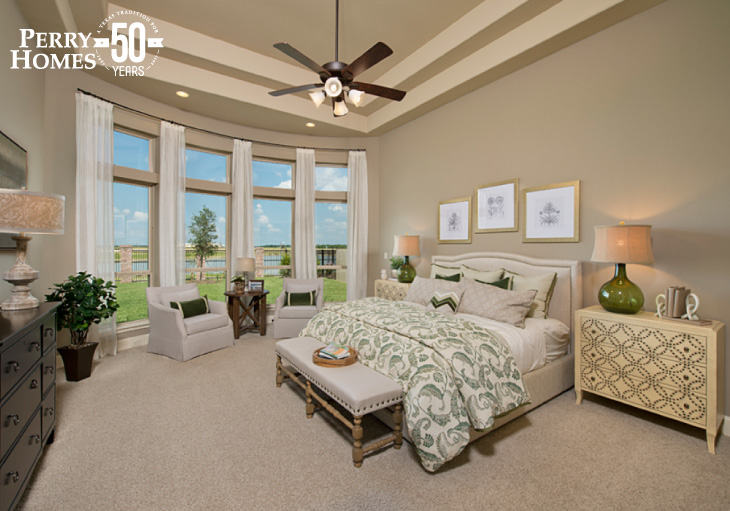 beige master bedroom with curved wall of windows, neutral  décor and view of community ponds