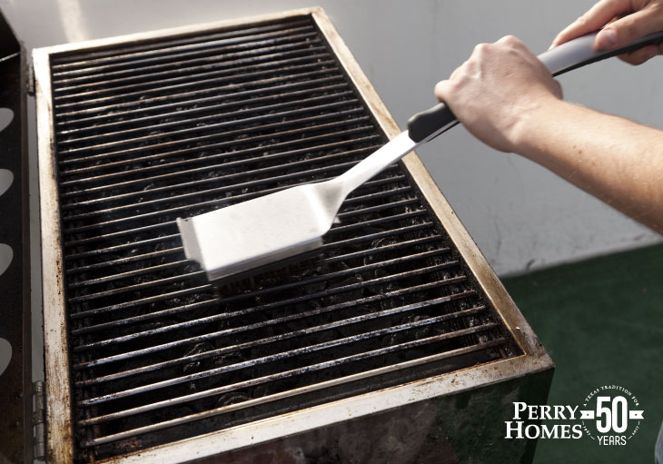 someone cleaning the grate of a grill with a brush