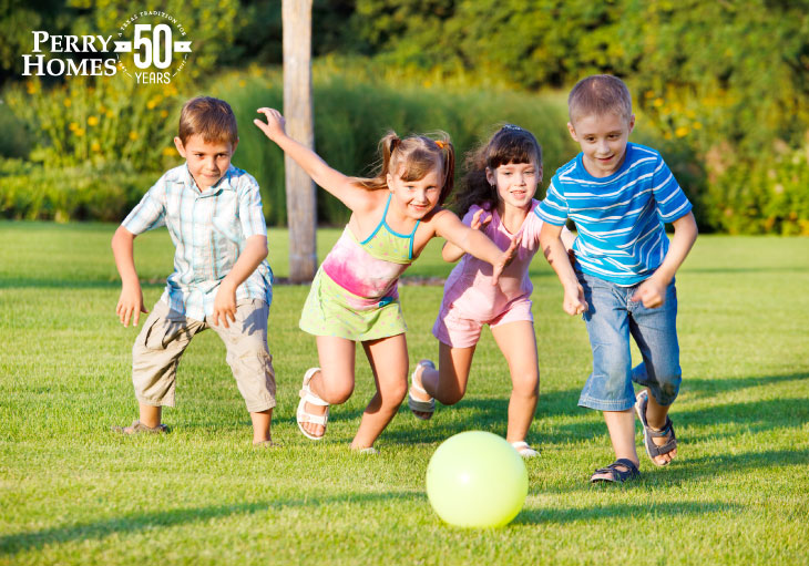 four children chasing a ball in a lawn