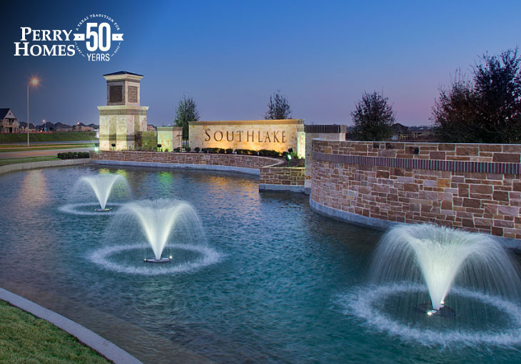 southlake community monument with brick wall, pond and three fountains illuminated at night