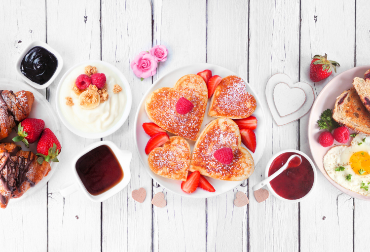 A plate with four heart-shaped pancakes and strawberries.