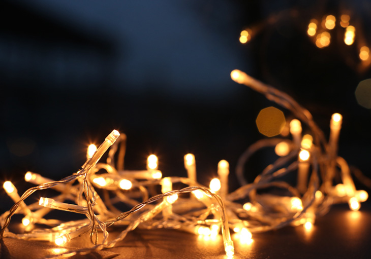 A tangled string of yellow Christmas lights in Houston sits atop a wood table.
