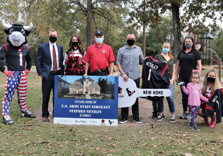 Houston Texans mascot, cheerleader, business representatives and Army veteran with family stand for a group photo.