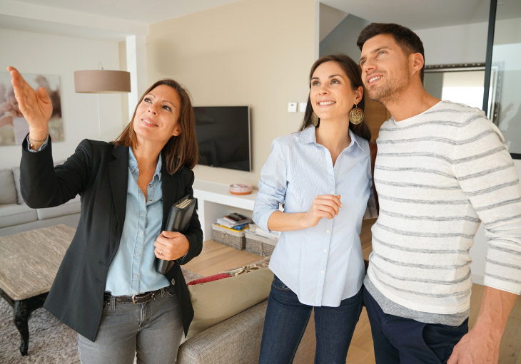 young couple with female real estate agent shoing the features of the inside of a furnished home