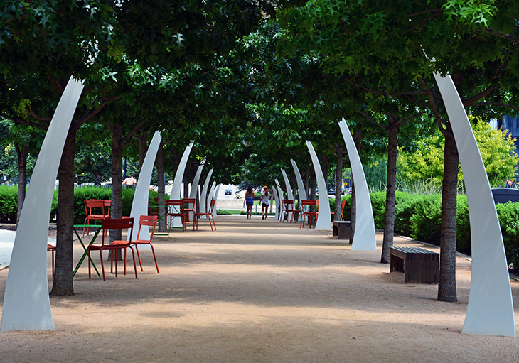 Tree-lined pathways and skyscrapers surround a large green area at Klyde Warren Park, just one of the best parks in Dallas, T