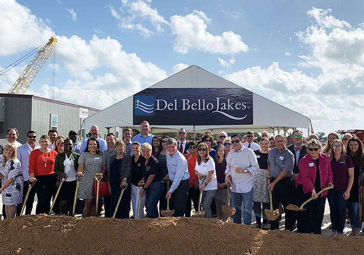 Diverse group of people with shovels at Del Bello Lakes community groundbreaking.