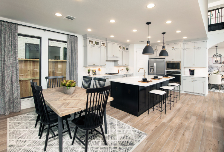 An open-concept kitchen in Texas features recessed lighting, white cabinets and a black kitchen island.