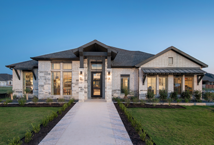 A home featuring Perry Homes' Hill Country design stands among green grass and blue skies as evening approaches.