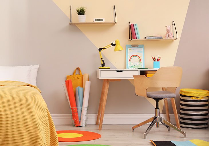 colorful children’s space in a Texas home with modern desk, yellow lamp, rainbow drawing, hanging shelves and striped hamper.