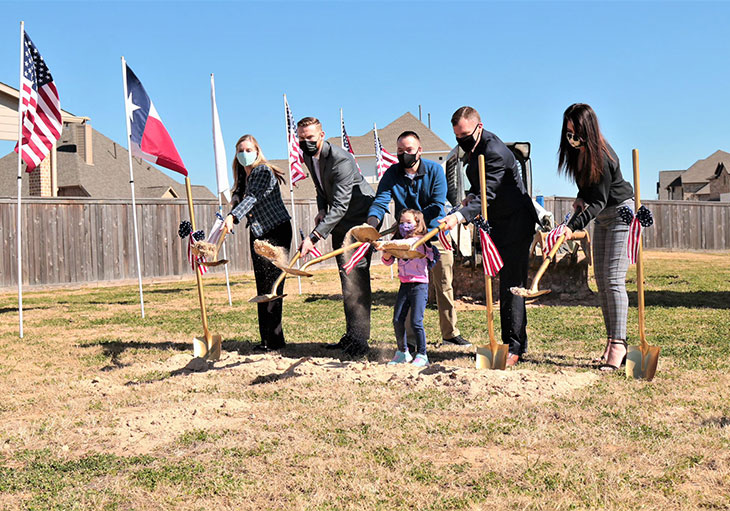 Perry Homes representatives, Stephen Netzley and daughter lifting shovels with scoops of dirt on the new homesite.