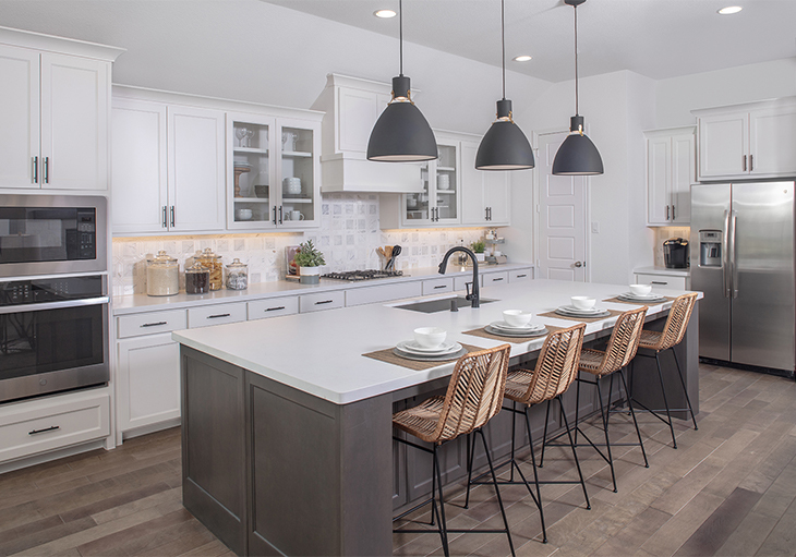 Modern, neutral kitchen in a naturally lit Texas home with large island, white cabinets, stainless steel appliances and wicker barstools.